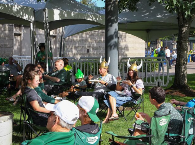 Tailgate attendees sitting and eating in Eugene before the Vikings played the Ducks.