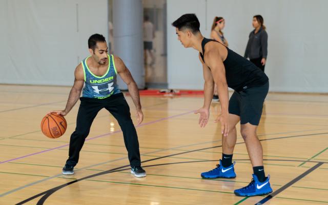 Two men playing basketball and one is guarding the other from moving.